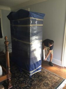 Mover wrapping furniture with professional packing materials.